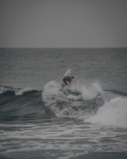 man surfing on sea waves during daytime