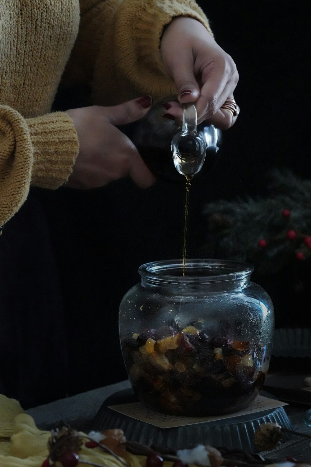 person holding clear glass jar with brown liquid