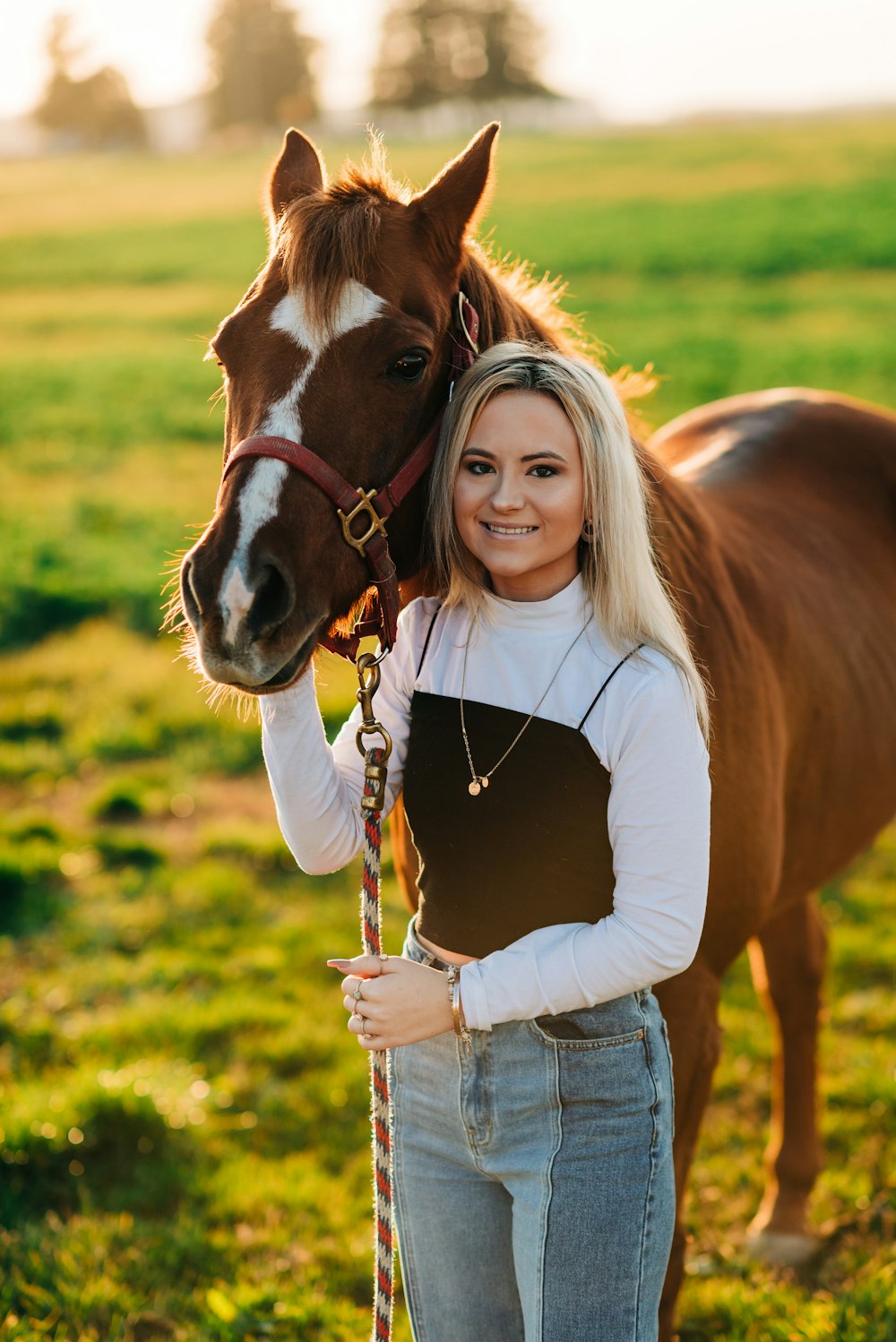 woman in black shirt and blue denim jeans standing beside brown horse during daytime