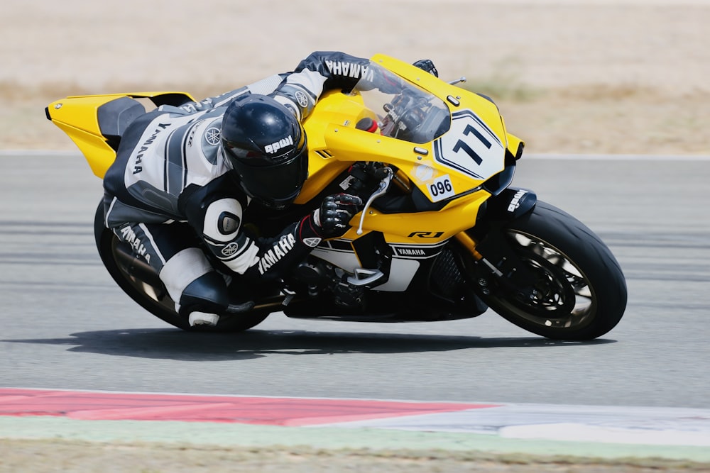 man in yellow and black motorcycle suit riding yellow and black sports bike