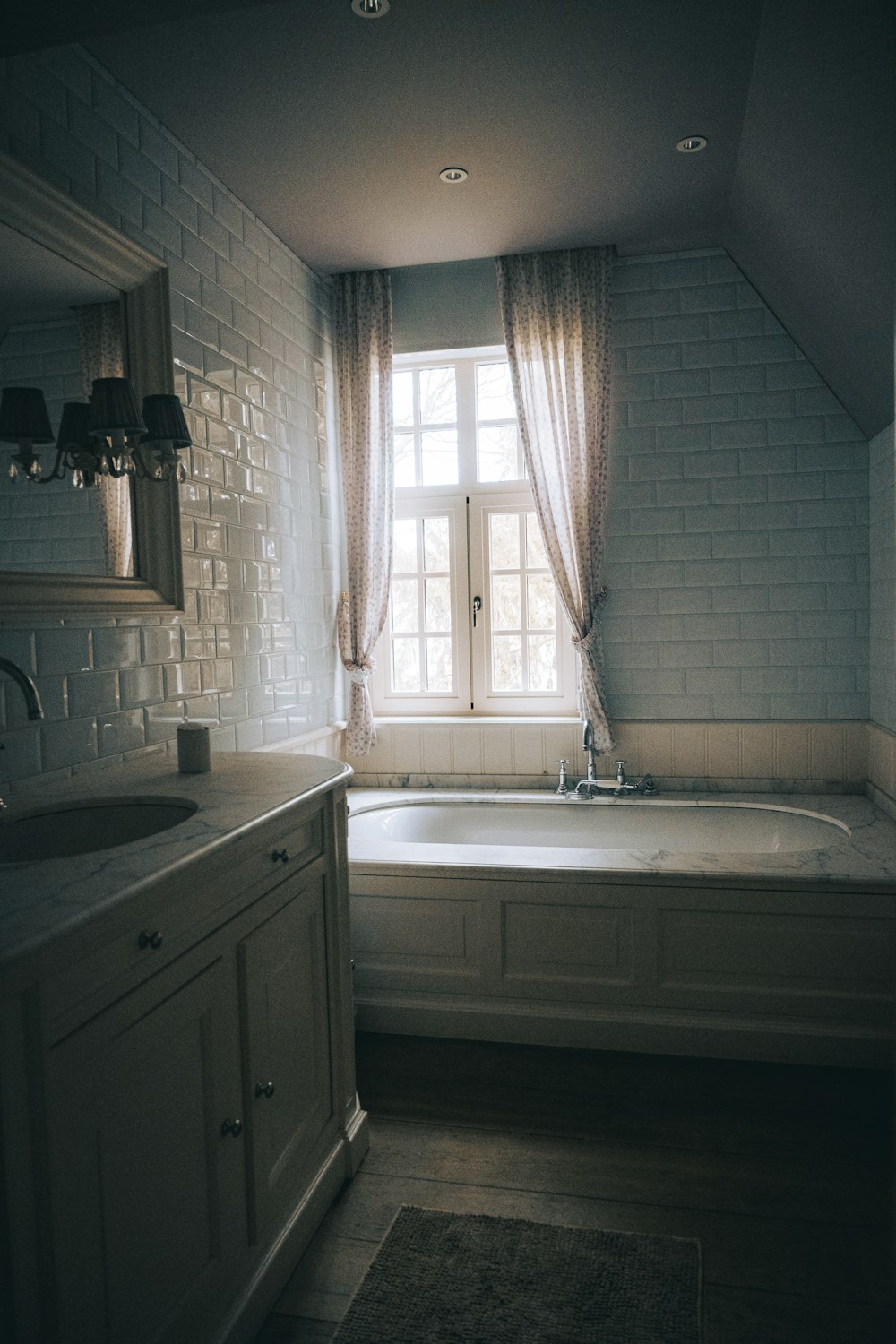 white bathtub near white window curtain