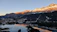 A serene sunrise over the snowy peaks of Saint Moritz, casting golden light on the frozen lake.
