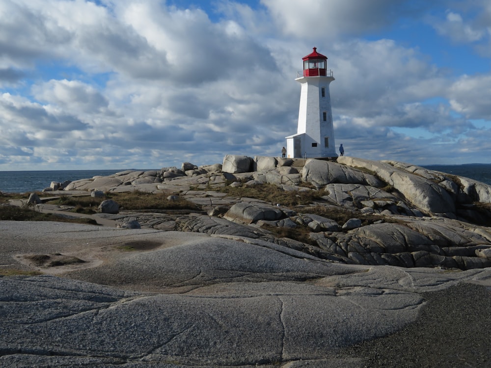 farol branco e vermelho na areia marrom sob o céu nublado durante o dia