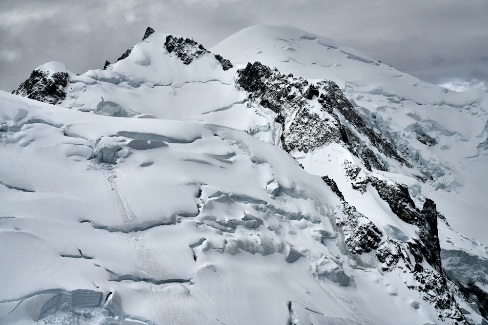 a large mountain covered in snow under a cloudy sky