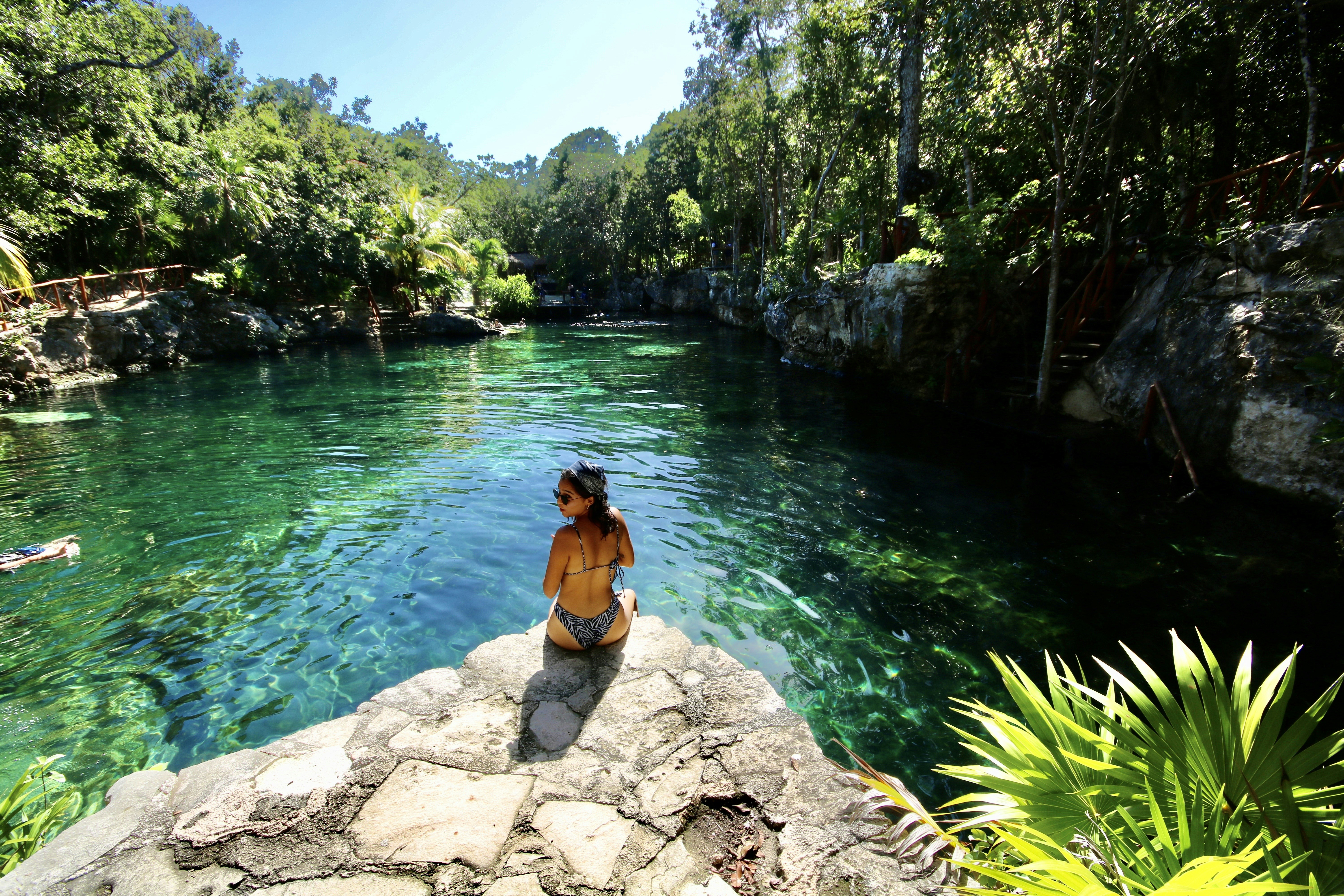 woman in black bikini sitting on rock near body of water during daytime, Cenote tortuga TULUM Quintana Roo, Caribe México 📸 Fernanda Loayza