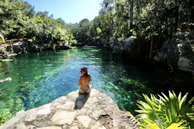 woman in black bikini sitting on rock near body of water during daytime