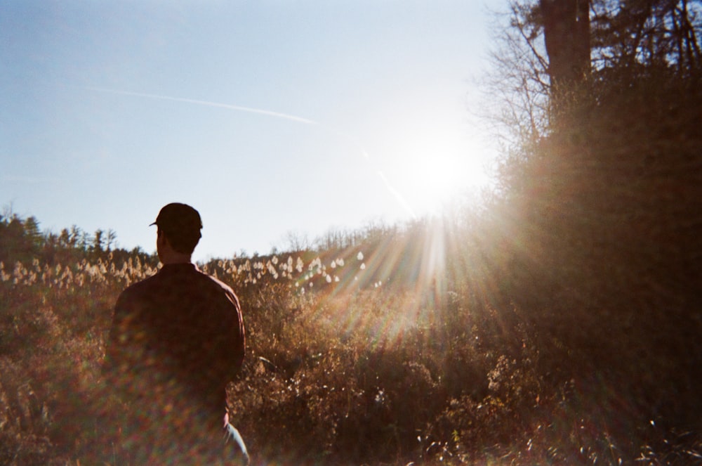 man in brown jacket standing on grass field during daytime