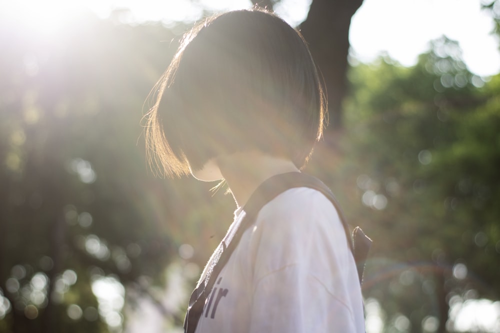 Mujer con camisa blanca mirando al sol