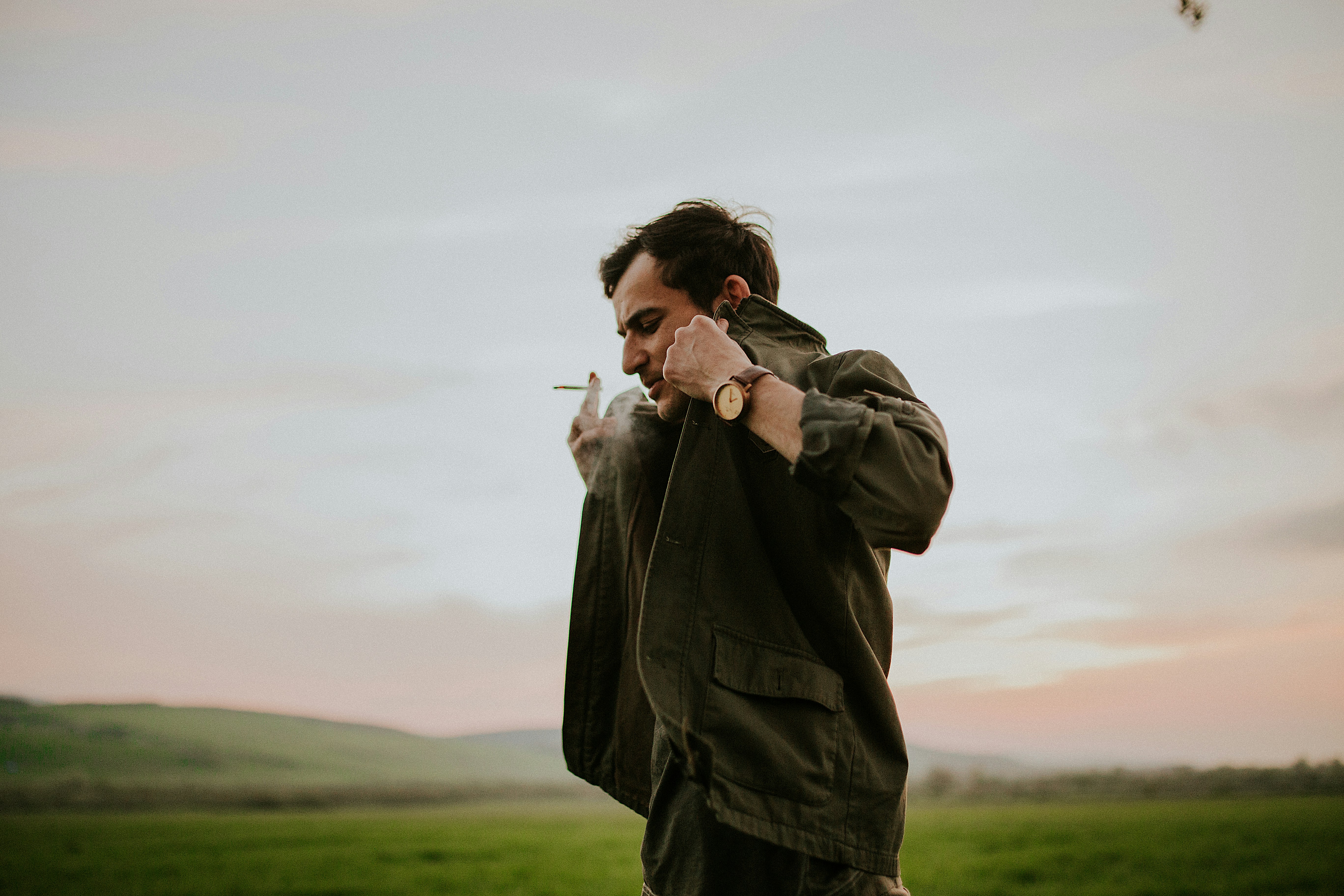 낮 동안 푸른 잔디밭에 서 있는 녹색 코트를 입은 남자