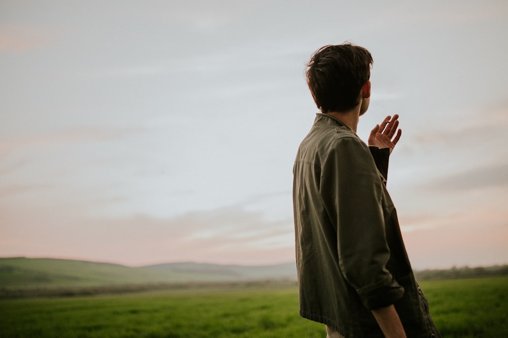 man in gray hoodie standing on green grass field during daytime