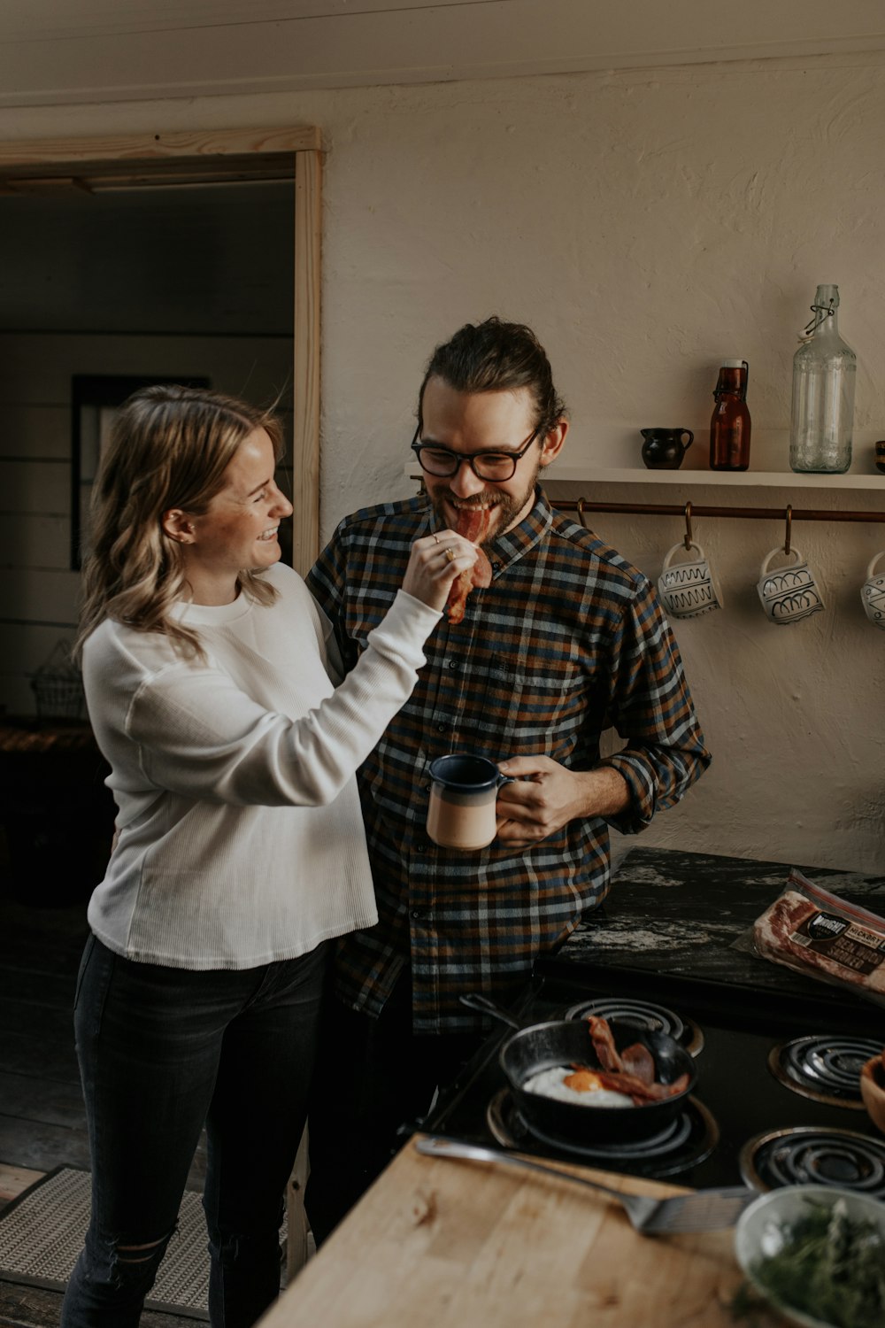 woman in white sweater holding man in black and white checkered dress shirt