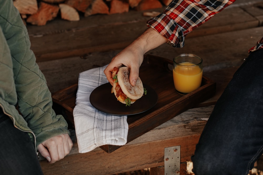 person holding burger on black plate