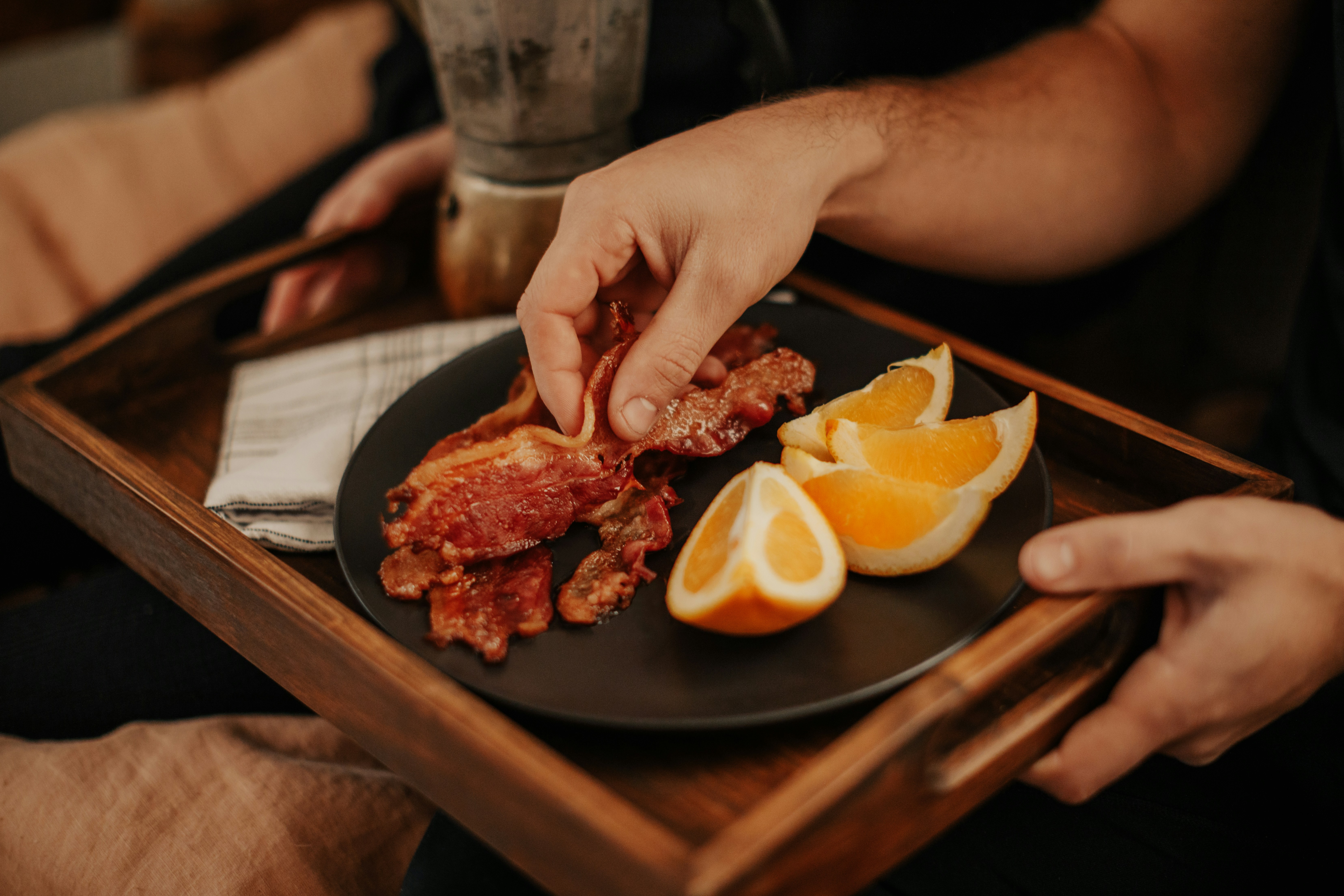 person slicing raw meat on black plate