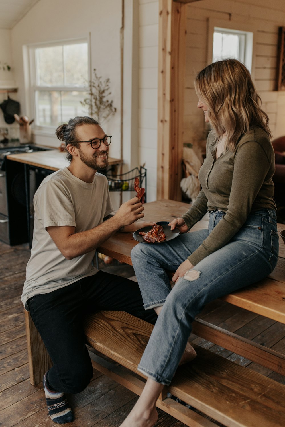 man in white crew neck t-shirt and blue denim jeans sitting on brown wooden bench