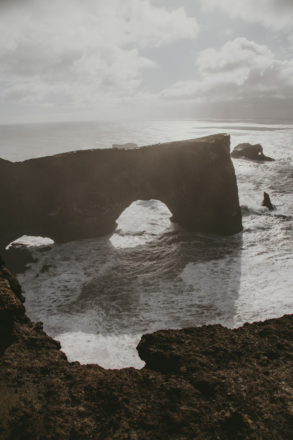 rock formation on sea under white clouds during daytime