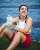 Energetic woman enjoying a protein shake after an intense workout outdoors.