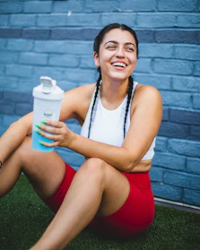 A vibrant image of a happy athletic woman enjoying a protein shake outdoors.