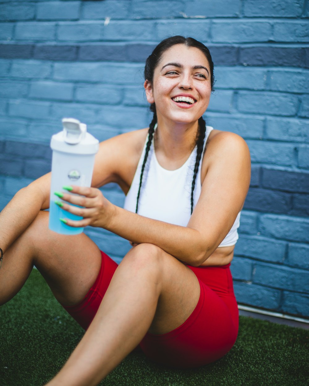 woman in white tank top and red shorts holding white plastic bottle