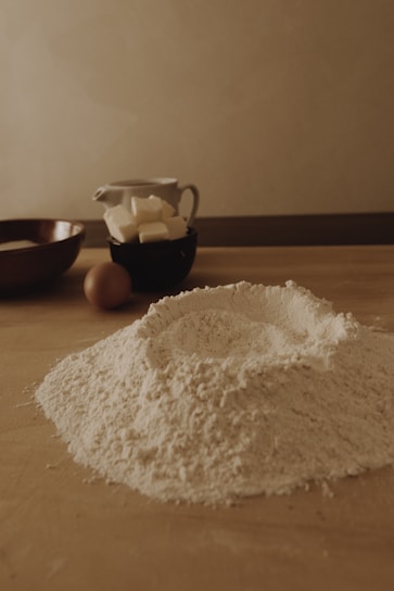 A warm kitchen scene with a freshly baked homemade cake on a wooden table, surrounded by baking ingredients in yellow and brown tones.