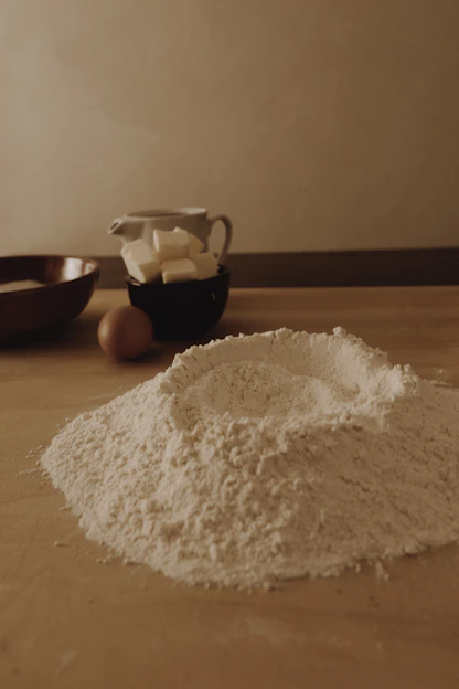 A warm, sunlit kitchen counter with baking tools, fresh ingredients, and a half-finished loaf of bread.