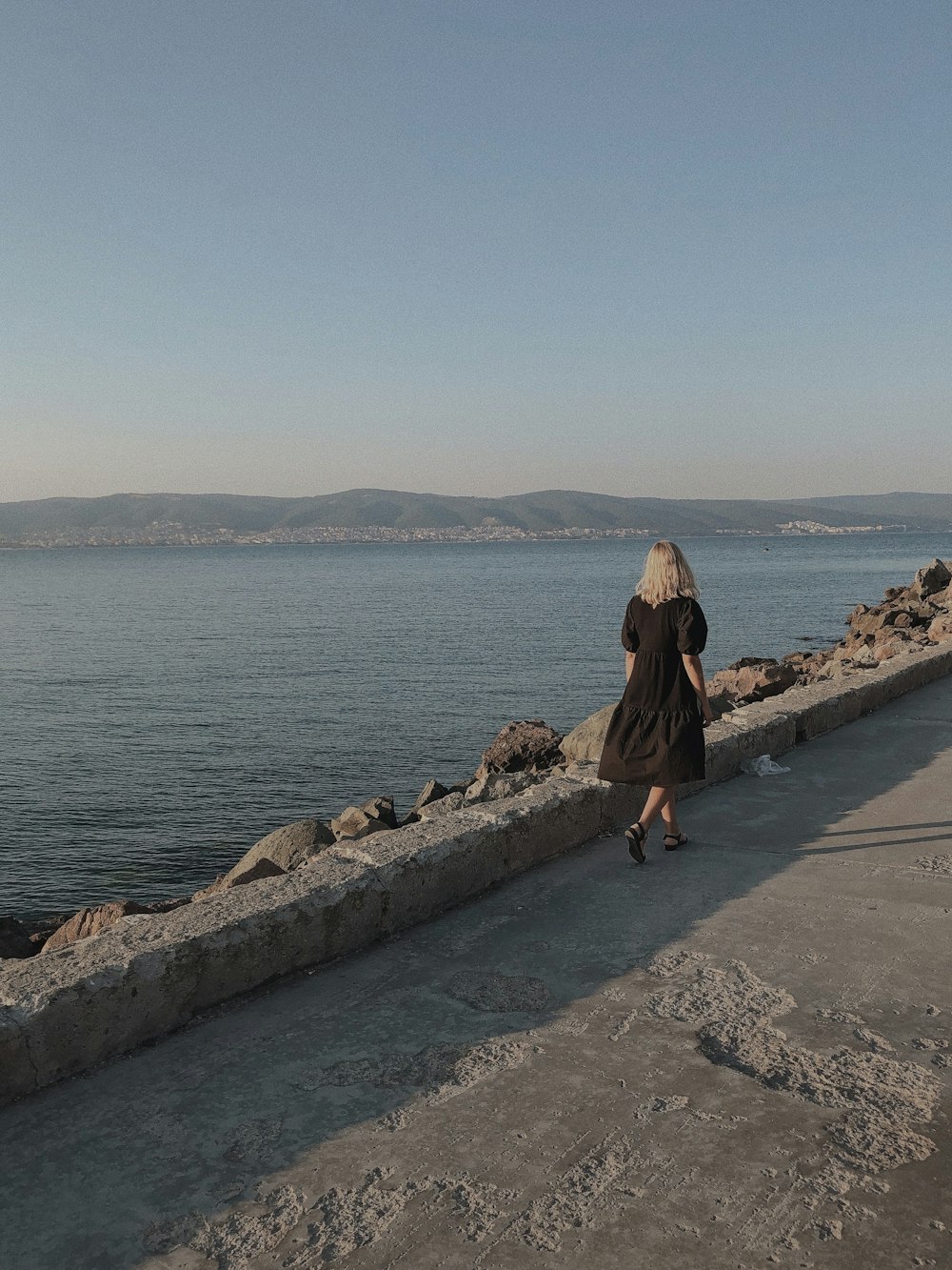 Mujer en vestido marrón de pie en el muelle de hormigón durante el día