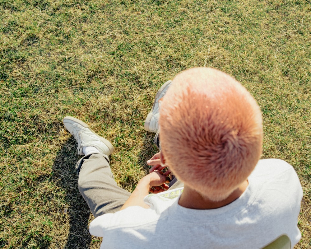 man in white shirt sitting on green grass field