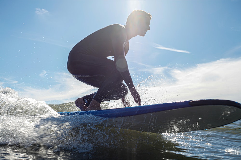 Hombre con traje de neopreno negro surfeando en el agua durante el día