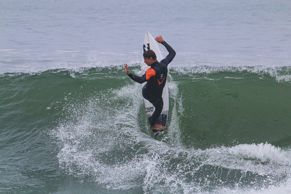 man in black wetsuit surfing on sea waves during daytime