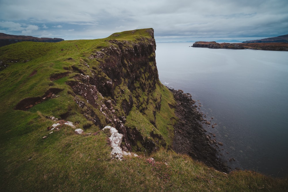 green grass covered mountain beside sea during daytime