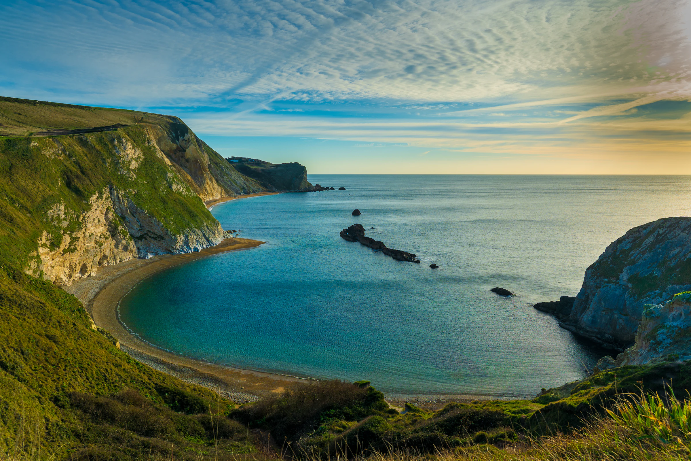 A coastal landscape of green cliffs above the sea