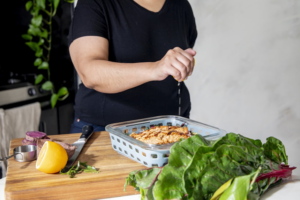 man in black crew neck t-shirt holding black plastic tray with food