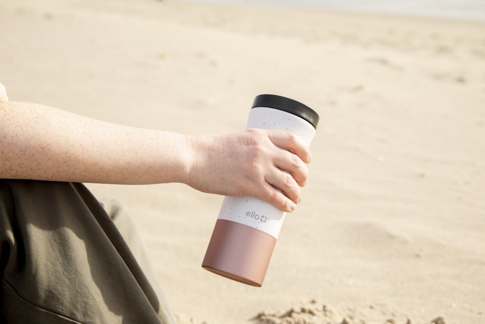 person holding white and black plastic cup