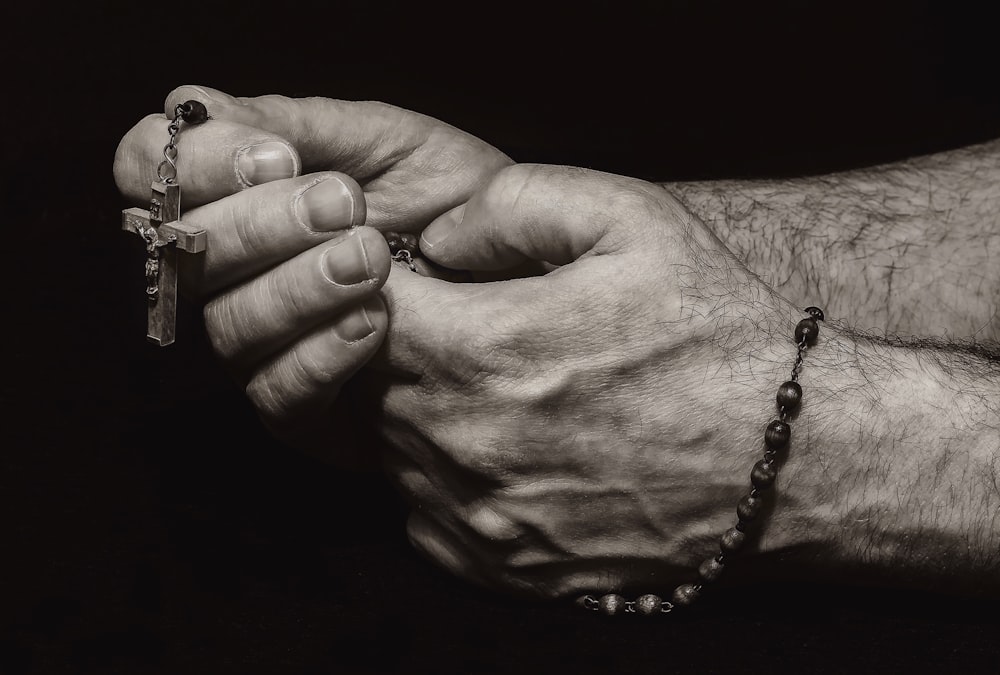 grayscale photo of person holding silver necklace