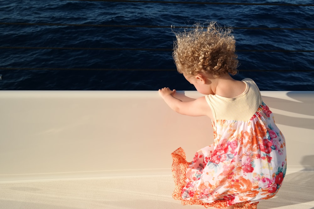 girl in white tank top and pink floral skirt standing on water during daytime