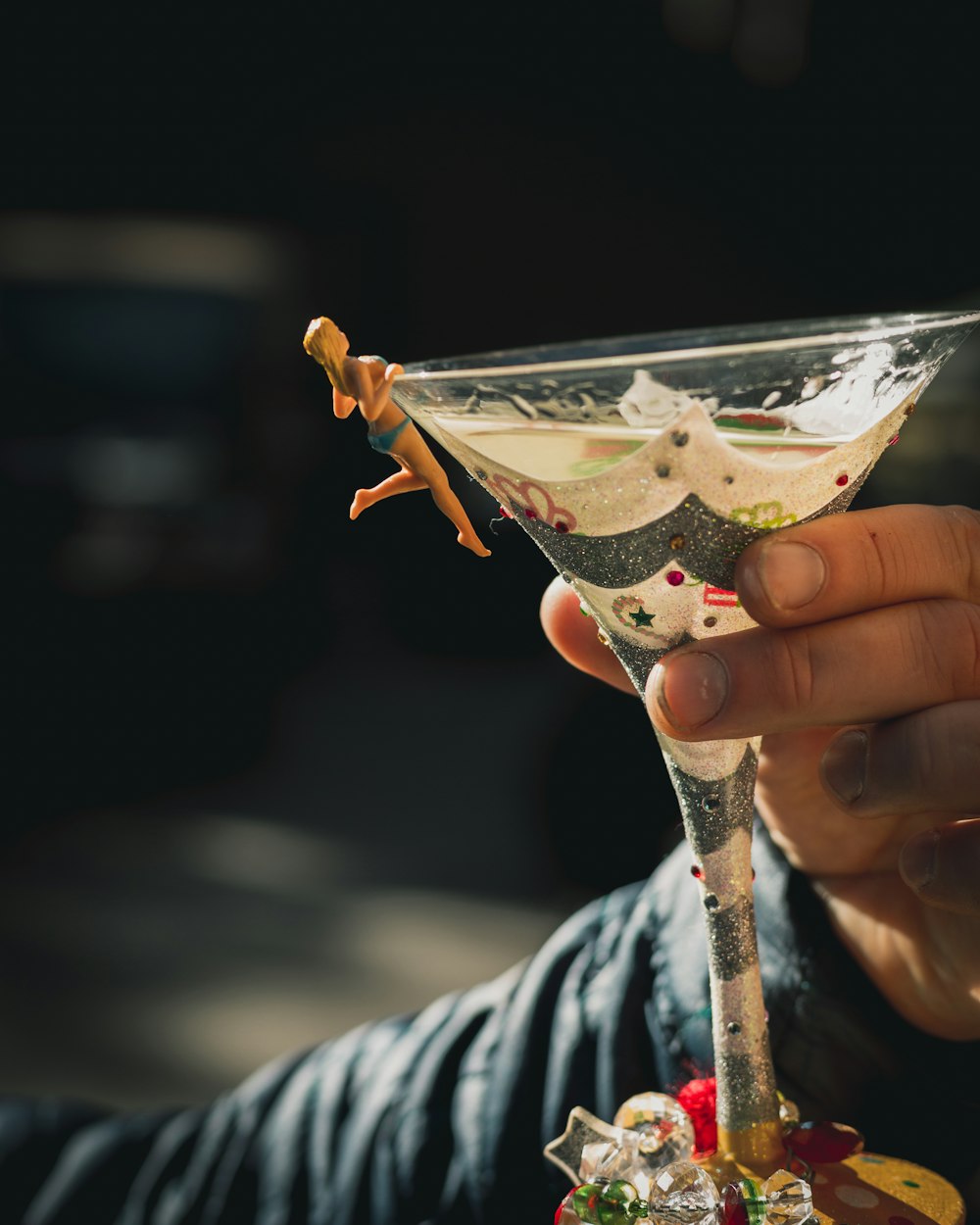 person holding clear cocktail glass with brown liquid