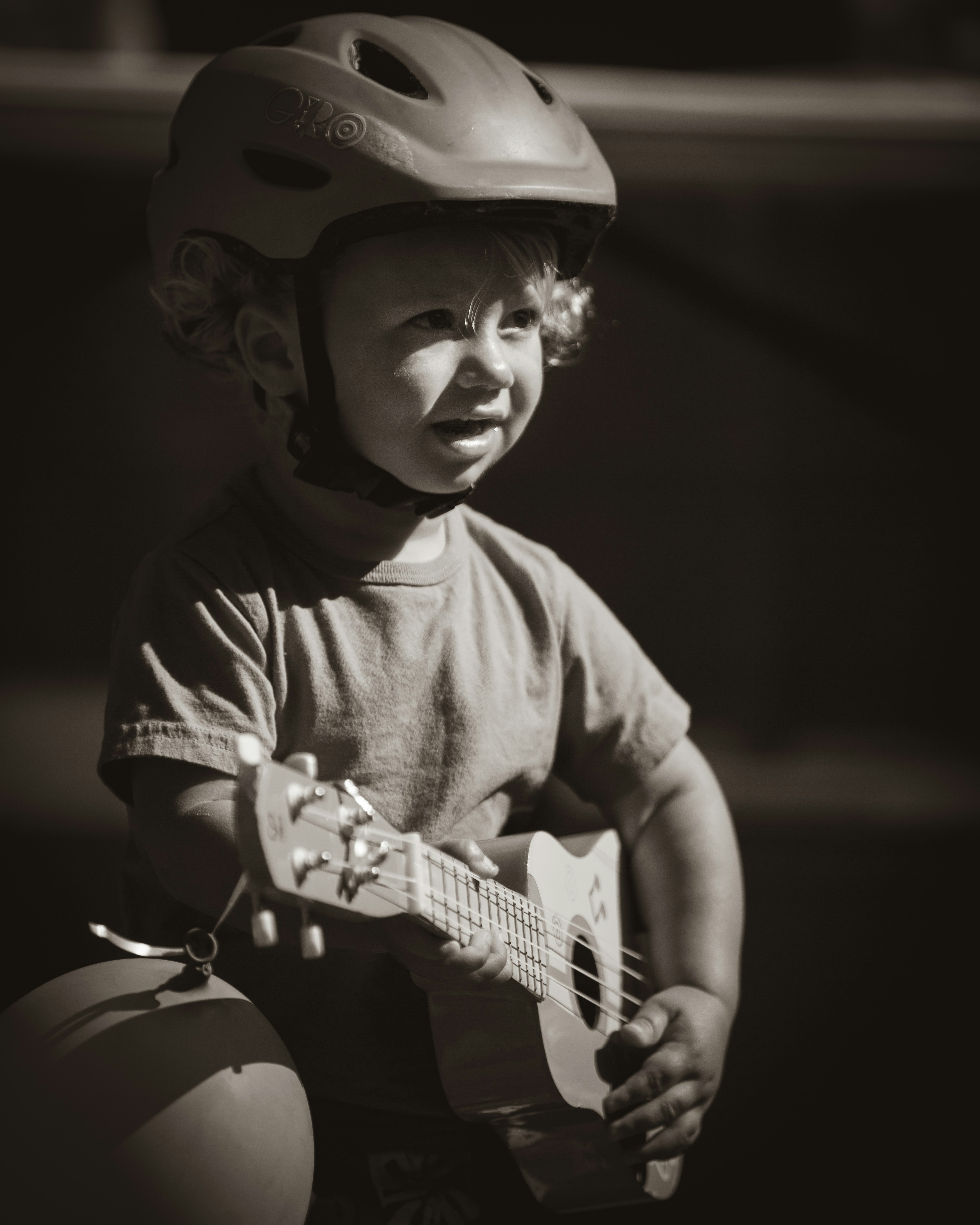 grayscale photo of boy playing guitar