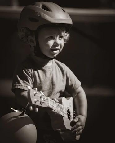 grayscale photo of boy playing guitar