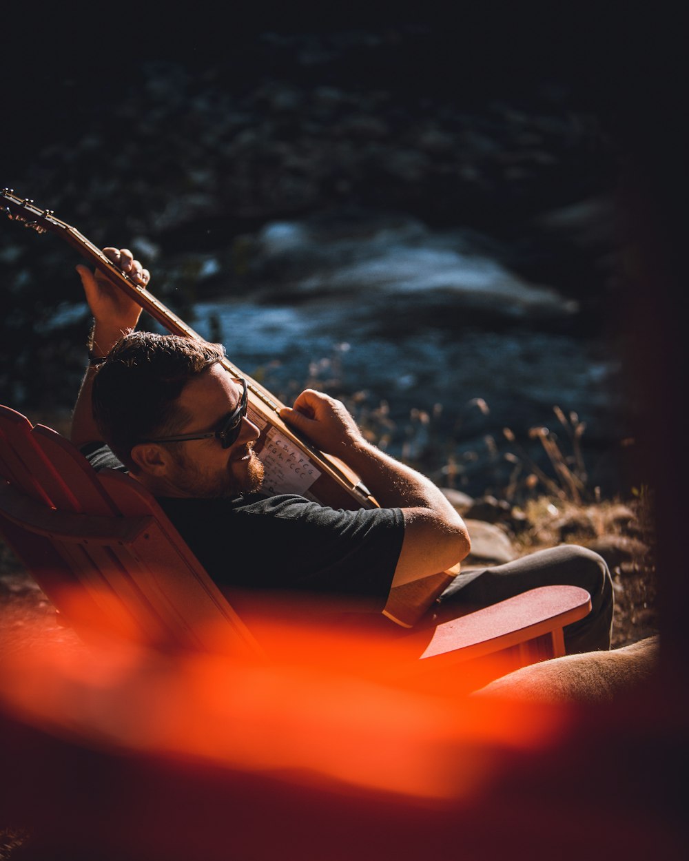 man in black tank top and blue shorts sitting on orange chair