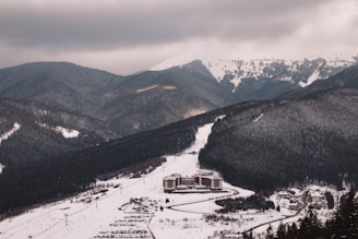 Snow-covered mountain resort with cozy cabins and skiers enjoying the slopes.