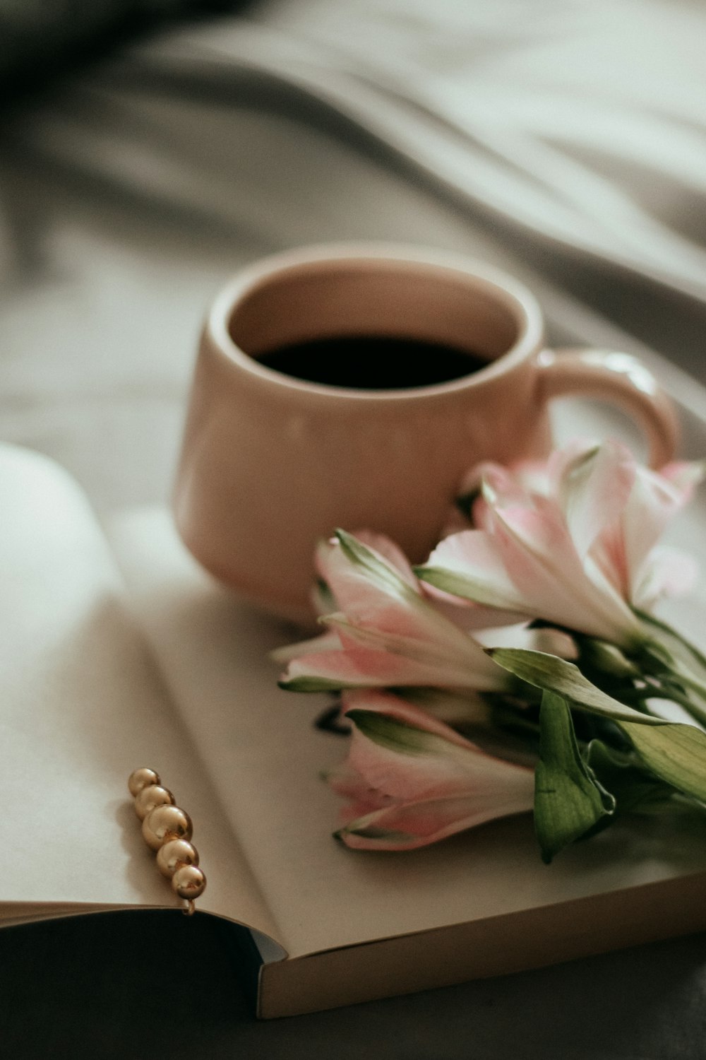 fiori rosa e bianchi accanto a tazza in ceramica marrone