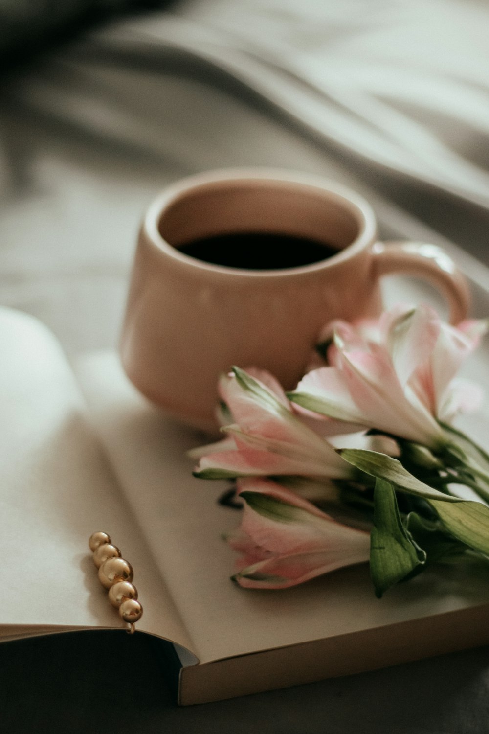 pink and white flowers beside brown ceramic mug