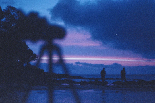 A behind-the-scenes shot of a film crew setting up a dramatic scene at sunset.