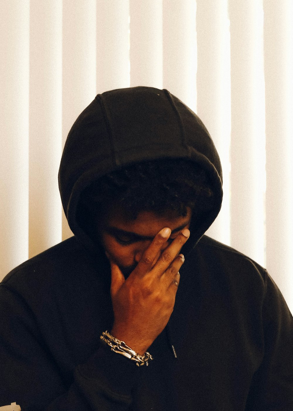 man in black hoodie covering his face