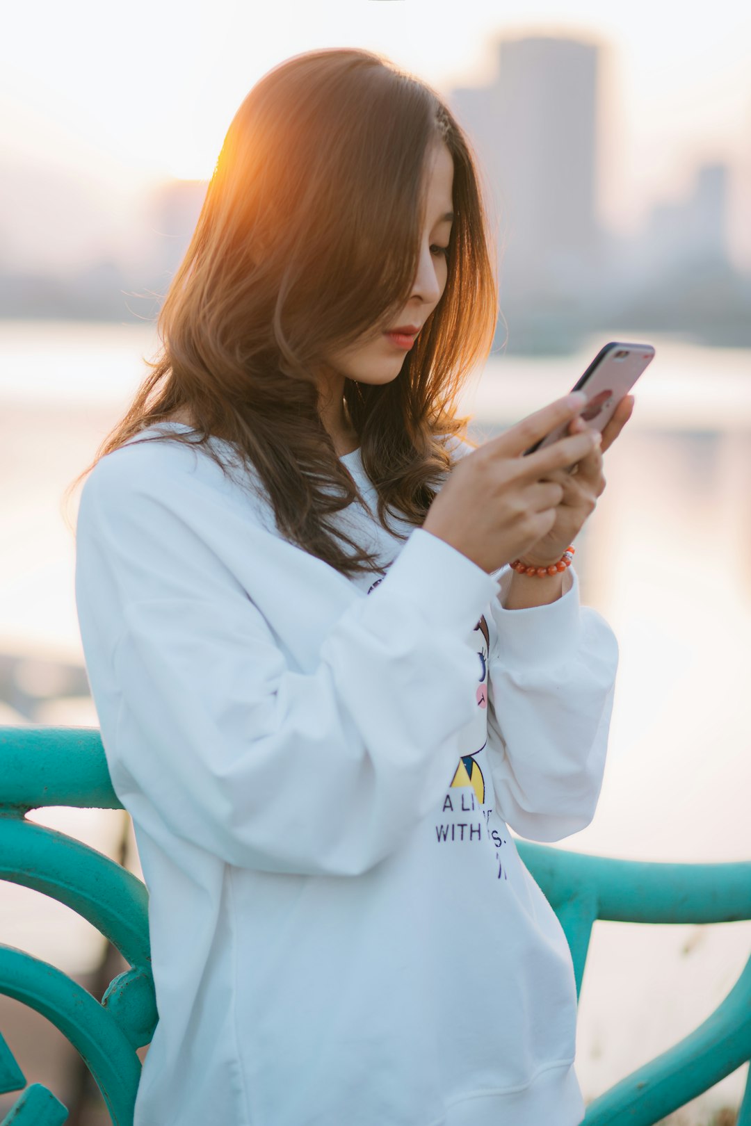 woman in white long sleeve shirt holding smartphone