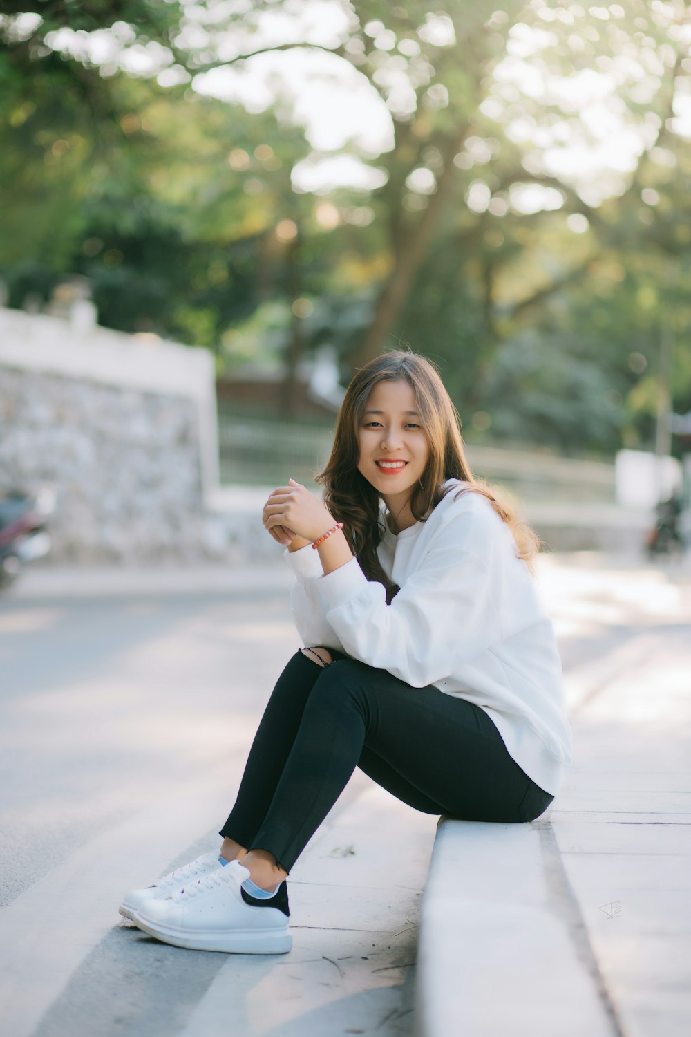 Woman in white long sleeve shirt and black pants sitting on gray concrete  floor during daytime photo – Free Grey Image on Unsplash