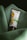 A tube of botanical scrub rests on a soft, green fabric. The packaging features an image of apricots and leaves, indicating it's a product with natural ingredients.