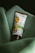 A tube of botanical scrub rests on a soft, green fabric. The packaging features an image of apricots and leaves, indicating it's a product with natural ingredients.