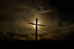 A serene biblical card featuring a softly glowing cross against a dawn sky.