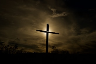 A serene image depicting a cross against a sunset.
