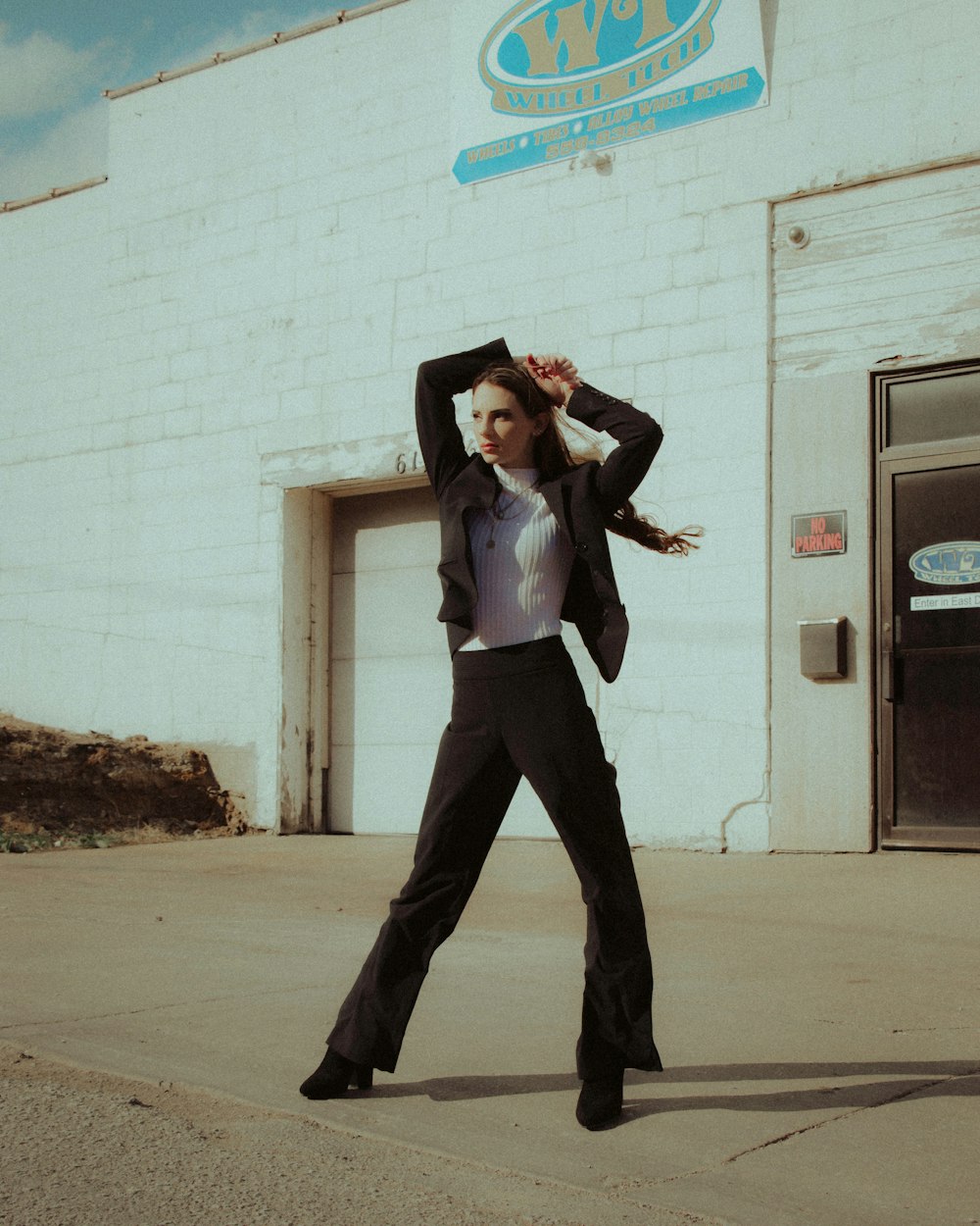 woman in white long sleeve shirt and black pants standing on gray concrete floor